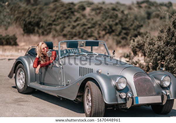 Beautiful lady in red dress near classic convertible\
vintage old car