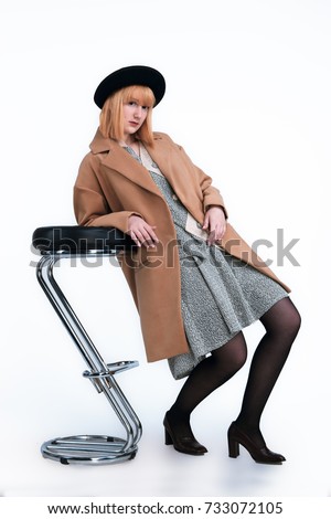 Beautiful lady in retro clothes with a chair and black hat