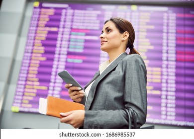 Beautiful lady with smartphone and plane ticket looking away and smiling stock photo