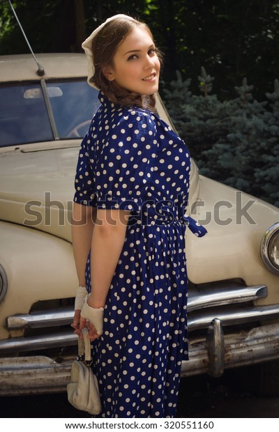 Beautiful\
lady in vintage dress standing near retro\
car