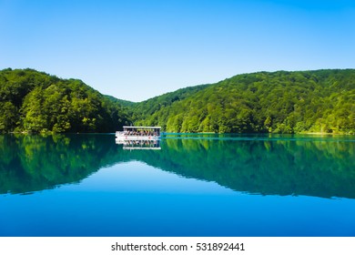 Beautiful lake with boat on the blue water between green hills. Plitvice Lakes, Croatia.