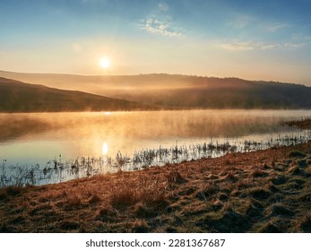 Beautiful lake in golden hour. Mist and fog above the lake. Soft sunlight, golden hour. Nature, climate change, environment. Landscape water reservoir at sunrise. - Powered by Shutterstock