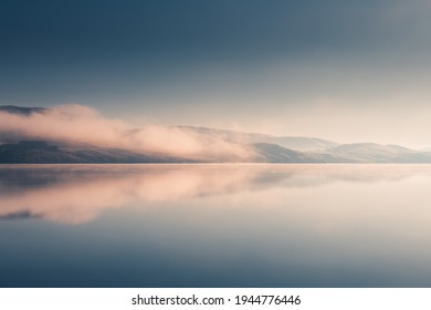 Beautiful lake in misty morning. Mountains and clouds are reflected in the calm water surface. Autumn landscape. South Ural, Russia. - Shutterstock ID 1944776446