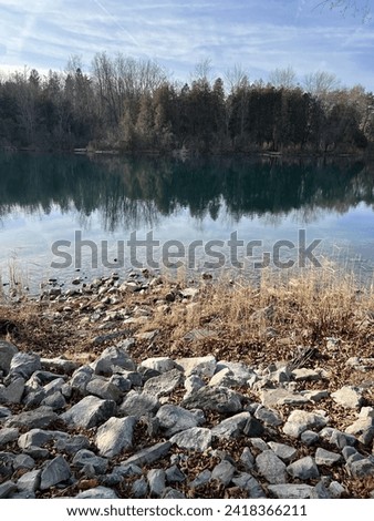 Beautiful Lake Scene with rocky beach in the foreground and treelined shore in the background. 