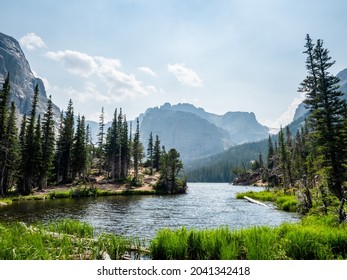 A beautiful lake scene surrounded by grass, pine trees, and mountains in Colorado. - Powered by Shutterstock