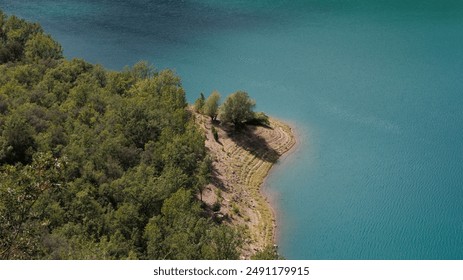Beautiful lakeside scene featuring clear, blue water and dense, green foliage in a serene, natural setting. - Powered by Shutterstock