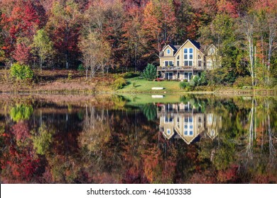 A Beautiful Lakeside Vacation Home Nestled Among Colorful Trees Displaying Autumn Foliage.  