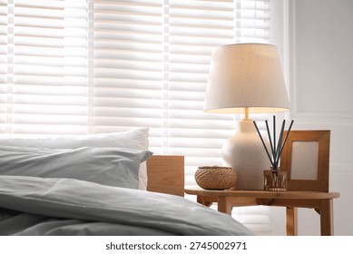 Beautiful lamp, frame and aroma diffuser on bedside table at home