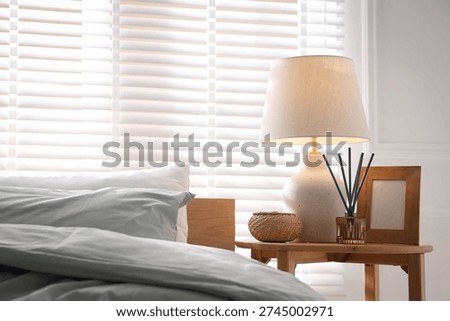 Beautiful lamp, frame and aroma diffuser on bedside table at home