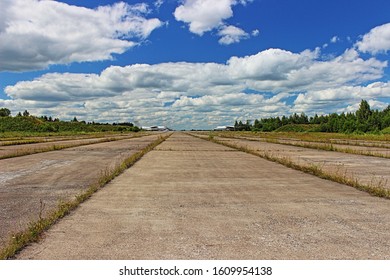 Beautiful Landscape Abandoned Empty Concrete Slab Tarmac Runway With Airplanes On Horizon On Blue Cloudy Sky Background On Sunny Summer Day