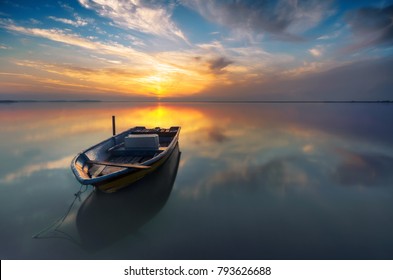 Beautiful landscape of the beach at morning. Fisherman boat and clouds reflecting in the water. Long exposure. - Powered by Shutterstock