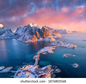 Beautiful landscape with blue sea, snowy mountains, rocks and islands, village, rorbu, road, bridge and pink sky. Aerial view. Hamnoy in snow at sunrise in winter in Lofoten islands, Norway. Top view - Powered by Shutterstock