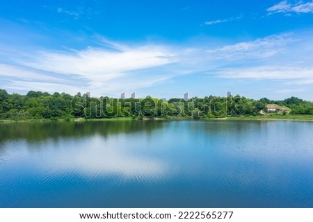 Beautiful landscape with blue water lake and blurry reflection of meadow and forest surrounding it on the mountain