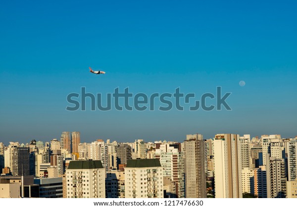 Beautiful landscape in the city, airplane and moon on a\
sunny day. 