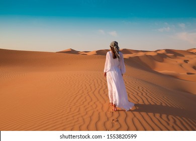 Beautiful landscape in desert. Amazing dune Moreeb in United Arab Emirates. Golden waves of sand. Nature safari panorama. Sexy woman enjoys view Liwa oasis. Unique travel. 