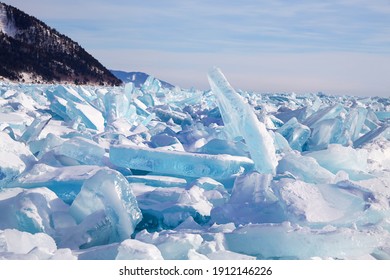 Beautiful Landscape Of The Frozen Lake Baikal On A Sunny Winter Day. Piles Of Blue Ice Fragments Covered In Snow.