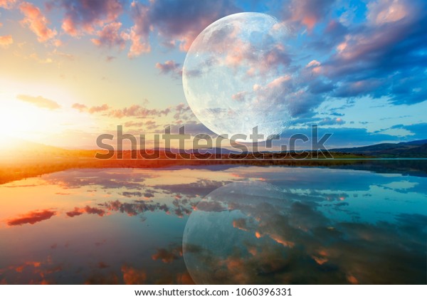 Beautiful landscape with full moon (super moon)\
reflection on the water surface at amazing sunset   \