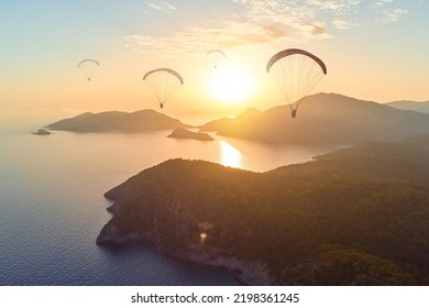 Beautiful Landscape Of Group Of Paragliders Flying Among Idyllic Mountains In The Sea Lagoon In Haze At Sunset. Soft Focus Wallpaper 