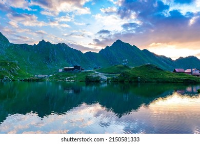 Beautiful landscape of high mountains at sunset. View of Balea glacier lake with chalets located at pass of Transfagarasan road, is one of most beautiful roads in world. Carpathians. Romania.