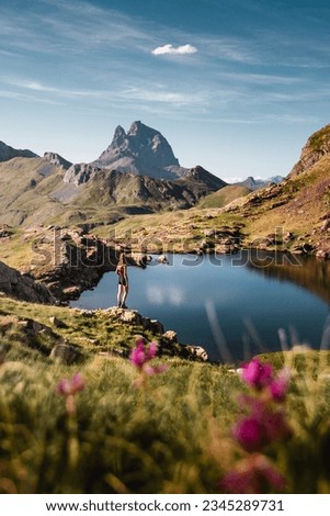 beautiful landscape of the ibones or lakes of anayet with the Midi d'Ossau peak in the background and pink flowers in the foreground and a girl enjoying the Pyrenees Mountains Stock foto © 