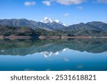 Beautiful landscape of lake and reflection of blue sky, clouds and mountains on surface of lake, Panoramic view of lake and snow-covered mountain and Forest trees calm in Jijel Algeria North African.