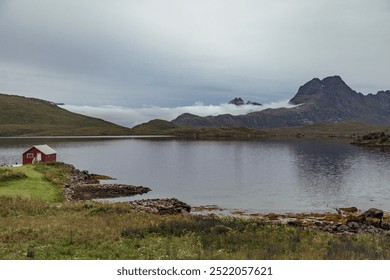 Beautiful Landscape in Lofoten Islands, Showcasing a Serene Lake, Rolling Hills, and Majestic Mountains Under a Cloudy Sky - Powered by Shutterstock