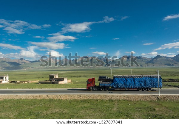 Beautiful landscape of\
mountains in Qinghai, China. Sunny blue sky with clouds. Stunning\
view of Tibetan Plateau with road and car. Taken from Qinghai-Tibet\
railway. 