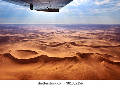 Beautiful landscape of the Namib Desert under the wing of the aircraft at sunset. Flying on a plane over the desert is one of the most popular tourist attractions in Namibia