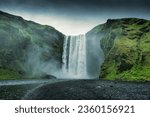 Beautiful landscape of powerful Skogafoss waterfall with Skoga river flowing from cliff in summer on gloomy day at Iceland