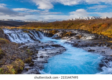 A beautiful landscape scene of the Bruarfoss Waterfall on rocks against a blue cloudy sky in Brekkuskogur, Iceland