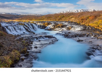 A beautiful landscape scene of the Bruarfoss Waterfall on rocks with majestic water and a blue cloudy sky in Brekkuskogur, Iceland