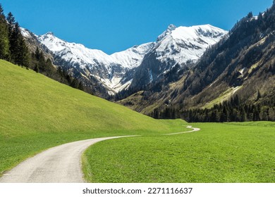 Beautiful landscape with snow capped mountains, green grass meadows and hiking trail in springtime. Trettachtal, Allgaeu, Bavaria, Germany. - Powered by Shutterstock
