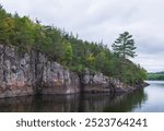 Beautiful landscape of the St. Croix River showing ancient basalt and igneous cliffs of Interstate State Park formed during the Ice Age with trees growing from the rock; summer day in Taylors Falls,MN