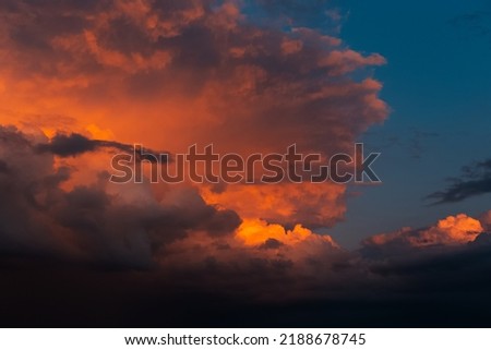 Beautiful landscape of sunset with dark colourful fluffy clouds. Natural background.