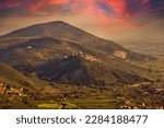 Beautiful landscape at sunset with red clouds of the village of Sermoneta with its castle and the Pontine plain under the mountains. Background photo useful for wallpapers.