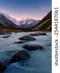 Beautiful landscape of vibrant sunset sky over Mount Cook with the moon and stream flowing in Hooker Valley Track at New Zealand