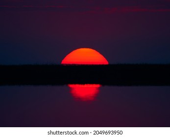 Beautiful landscape - water at sunrise - red and orange sky with sunlight reflecting on sea water