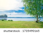 The beautiful landscape of a white simple wooden boat tied to a birch tree on the lake somewhere in the depths of Finland. Good summer day in nature. Concept vacation on the lake.