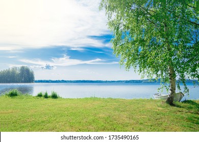 The beautiful landscape of a white simple wooden boat tied to a birch tree on the lake somewhere in the depths of Finland. Good summer day in nature. Concept vacation on the lake. - Shutterstock ID 1735490165