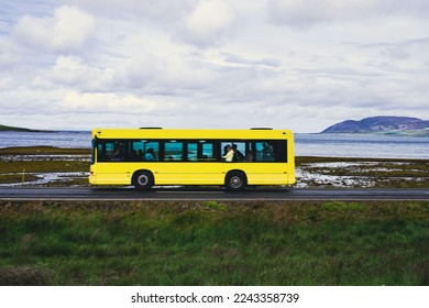 Beautiful landscapes with hills and mountains. Cloudy day. Yellow bus is moving with people inside 