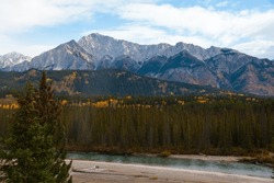 Beautiful Lanscape In The Rocky Mountains - Cloudy Sky, Spruce Forest And Yellow Poplar Trees In The Autumn, And Blue Waters Of The River.