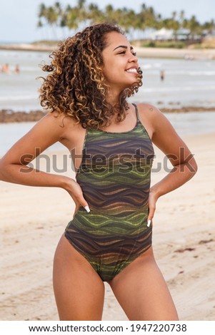 beautiful Latin American woman in bikini on the beach. Young woman enjoying her summer vacation on a sunny day, smiling and looking at the camera
