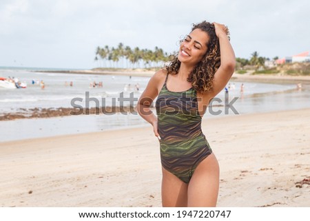 beautiful Latin American woman in bikini on the beach. Young woman enjoying her summer vacation on a sunny day, smiling and looking at the camera
