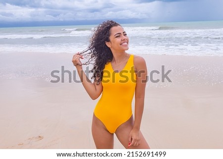 beautiful Latin American woman in bikini on the beach. Young woman enjoying her summer vacation on a sunny day, smiling and looking at the camera