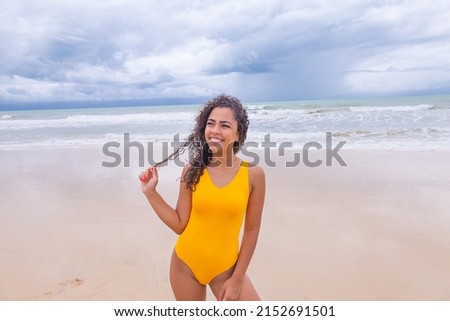 beautiful Latin American woman in bikini on the beach. Young woman enjoying her summer vacation on a sunny day, smiling and looking at the camera