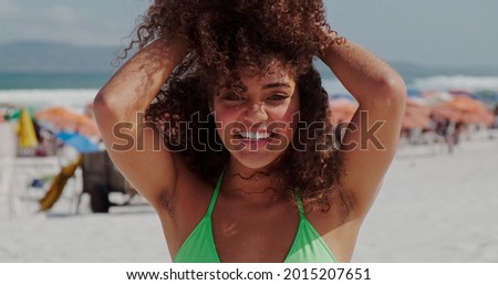 Beautiful Latin American woman on the beach. Young woman enjoying her summer vacation on a sunny day, smiling and looking at the camera