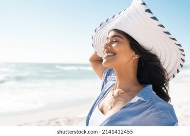 Beautiful latin hispanic woman wearing white straw hat at seashore with copy space. Young smiling woman on vacation enjoy sea breeze. Close up face of stylish woman wearing  fashion straw hat at beach - Shutterstock ID 2141412455