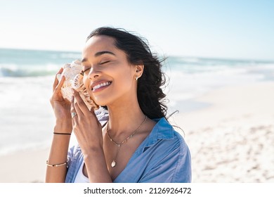Beautiful latin woman hearing the sound of the sea with a big seashell at beach. Hispanic girl on seacoast with a cockleshell in hands with copy space. Woman on a white sand beach holding a sea shell. - Shutterstock ID 2126926472