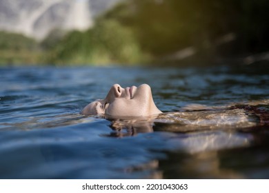 Beautiful Latin Young Woman Bathes In A Lake. Smiling Woman Lying On Her Back Floating In The Sea Water, Relaxing On A Beautiful Summer Day