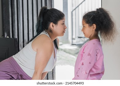 beautiful latina woman looking her brown-skinned daughter straight in the eye, admiring her beauty and proud to be her mother. girl gets advice from her mother about bullying.